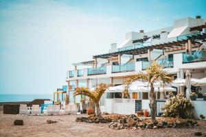 a hotel on the beach with palm trees and umbrellas at Apartment Mirador Del Castillo 3 El Cotillo in El Cotillo