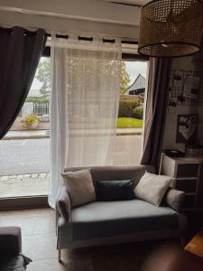 a couch sitting in front of a window at La Petite maison de Céline & Frédéric avec piscine à Préhy in Préhy