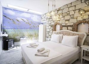 a bedroom with a large white bed with a stone wall at Bellezza Hotel Alaçatı in Alaçatı +95 photos