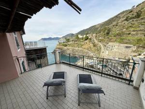 a balcony with two chairs and a view of the ocean at Mare Mosso 1 in Manarola +1 photo