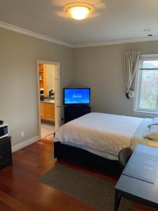 a bedroom with a bed and a flat screen tv at A cozy en-suite on the second floor with independent entranceclose to YVR in Richmond