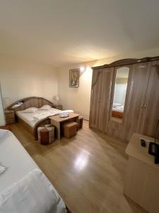 a bedroom with two beds and a table and a mirror at Hotel Decebal Bistrita in Bistriţa