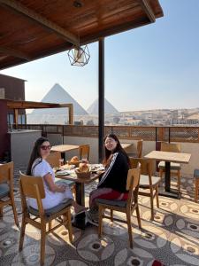 two women sitting at a table on top of a roof at Cheristo pyramids view inn in Cairo