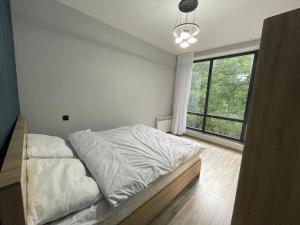 a bedroom with a bed with white sheets and a large window at Ismayil Shikhseyidov in Küsnǝt