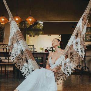 a woman in a dress sitting on a hammock at Casa do Cipó - Espaço Rio da Lua - São Jorge GO in Sao Jorge