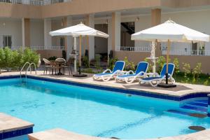 a swimming pool with lounge chairs and umbrellas at siriuspalaceluxor in Al Karnak