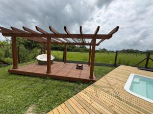 a wooden deck with a gazebo and a swimming pool at Chalé Rústico com Piscina Aquecida e Hidro in Araranguá