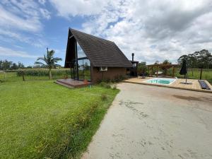 a small house with a swimming pool in a yard at Chalé Rústico com Piscina Aquecida e Hidro in Araranguá