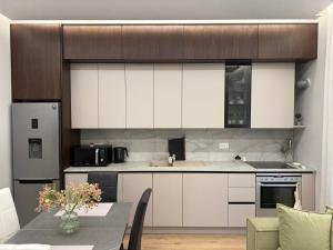 a kitchen with white cabinets and a table in a room at TheCozy Home Tirana in Sauk