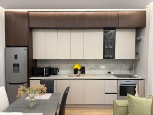 a kitchen with white cabinets and a table in a room at TheCozy Home Tirana in Sauk