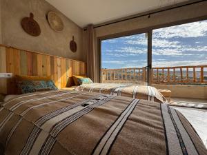 a bedroom with two beds and a large window at Manapany Surf Camp in Tamraght Ouzdar