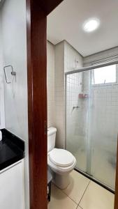 a bathroom with a toilet and a glass shower at Flat Premium no Centro Tudo a Pé in Montes Claros