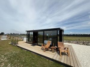 a cabin with two chairs on a wooden deck at Ultimate Vineyard Escape - Waipara in Waipara