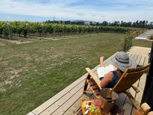 a person sitting in a chair reading a book on a table at Ultimate Vineyard Escape - Waipara in Waipara +11 photos