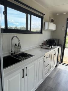 a kitchen with white cabinets and a sink and a window at Ultimate Vineyard Escape - Waipara in Waipara