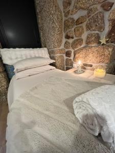 a bedroom with two beds with a stone wall at Senhora da Estrela AL in Seia