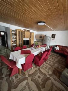 a dining room with a table and red chairs at Casa de sub pădure in Valcea