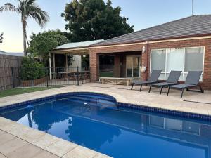 a swimming pool with two chairs and a house at Solara Retreat Mildura in Mildura