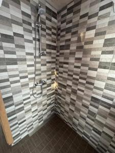 a shower in a bathroom with a checkered wall at EstBerg Tartu Glasshouse with Sauna in Tartu
