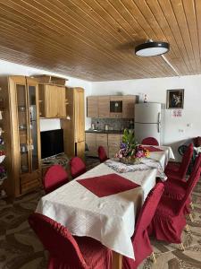 a kitchen with a table with red chairs and a refrigerator at Casa de sub pădure in Valcea