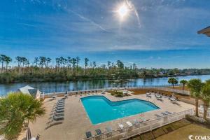 a swimming pool next to a river with chairs at Myrtle Beach Waterway Getaway in Myrtle Beach