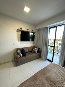 a living room with a couch and a flat screen tv at Mana Beach Experience in Ipojuca