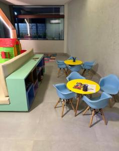 a classroom with two yellow tables and blue chairs at Mana Beach Experience in Ipojuca