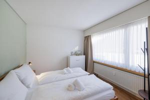 a bedroom with two white beds and a window at Brentsch A29 in Scuol +13 photos