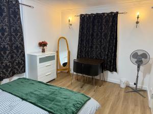 a bedroom with a bed and a mirror and a fan at Exquisite King-sized Bedroom - Free Parking in Dartford