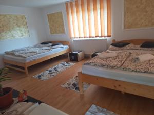 three beds in a room with wooden floors at Rajni Panzió in Praid