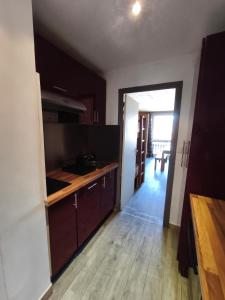 a kitchen with wooden cabinets and a door to a dining room at Studio cosy 6 pers au pied des pistes et vue exceptionnelle sur les Alpes à SUPERDÉVOLUY in Le Dévoluy +20 photos