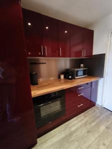 a kitchen with red cabinets and a microwave at Studio cosy 6 pers au pied des pistes et vue exceptionnelle sur les Alpes à SUPERDÉVOLUY in Le Dévoluy
