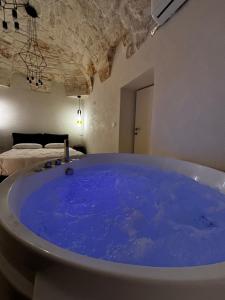 a large blue tub in a room with a bed at LEFKÓ OSTUNI, JACUZZI VISTA Mare in Ostuni +25 photos