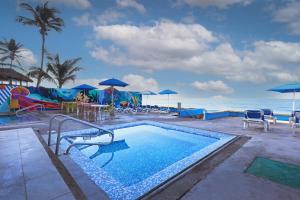 a swimming pool with tables and chairs and the ocean at Garner Hotel Mazatlan Beach by IHG in Mazatlán