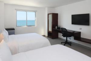 a hotel room with two beds and a desk with a computer at Garner Hotel Mazatlan Beach by IHG in Mazatlán