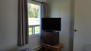 a tv sitting on top of a wooden stand next to a window at Northland Motel in Nipigon