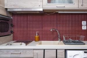 a kitchen with a sink and a red tiled wall at Mary's cozy apartment 2 in Pýrgos