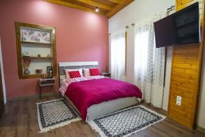 a bedroom with a bed with pink walls and a flat screen tv at Mary's cozy apartment 2 in Pýrgos +13 photos