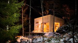 ein kleines Haus im Wald bei Nacht in der Unterkunft Panorama Studio - Sauna, Lakeview & Fireplace in Skaveröd