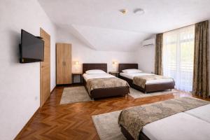 a hotel room with three beds and a flat screen tv at Motel Marić in Žepče