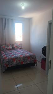 a bedroom with a bed with a floral bedspread and a window at Apto mobiliado 7min da Orla de Atalaia e 1min do Aeroporto in Aracaju +7 photos