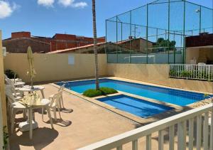 a swimming pool with a table and chairs next to a building at Apto mobiliado 7min da Orla de Atalaia e 1min do Aeroporto in Aracaju