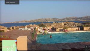 a rendering of a swimming pool with people in the water at CASA MUGHETTO R5055 WiFi, seafront, private sea access, swimming pool in La Maddalena +93 photos
