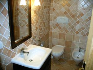 a bathroom with a sink and a toilet and a mirror at CASA MUGHETTO R5055 WiFi, seafront, private sea access, swimming pool in La Maddalena