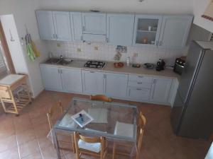 a kitchen with white cabinets and a table and a refrigerator at CASA MUGHETTO R5055 WiFi, seafront, private sea access, swimming pool in La Maddalena
