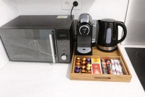 a microwave oven with a tray of drinks and a coffee maker at COSY LIVING in Huningue +16 photos