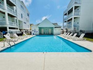 a large swimming pool with chairs and buildings at New Build with Rooftop Deck & Panoramic Ocean Views in Kill Devil Hills