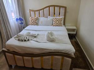 a large bed with a wooden headboard in a bedroom at Jay Homes - Modern & Cozy Apartments PGS Plaza - Nakuru CBD in Nakuru