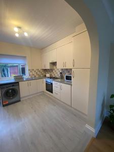 an empty kitchen with white cabinets and an archway at Spacious Dinnington bungalow in Dinnington