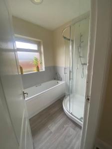a bathroom with a shower and a tub and a sink at Spacious Dinnington bungalow in Dinnington